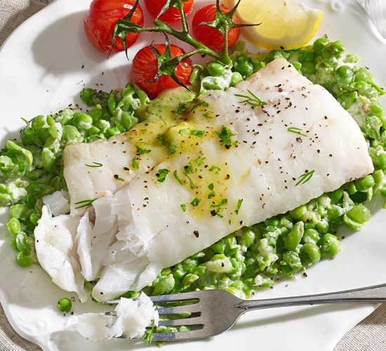 Cooked fish on bed of peas